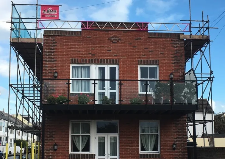 Rooftop scaffolding on a two-storey building with glass balcony in West Sussex by A-Star Scaffolding Southern Ltd