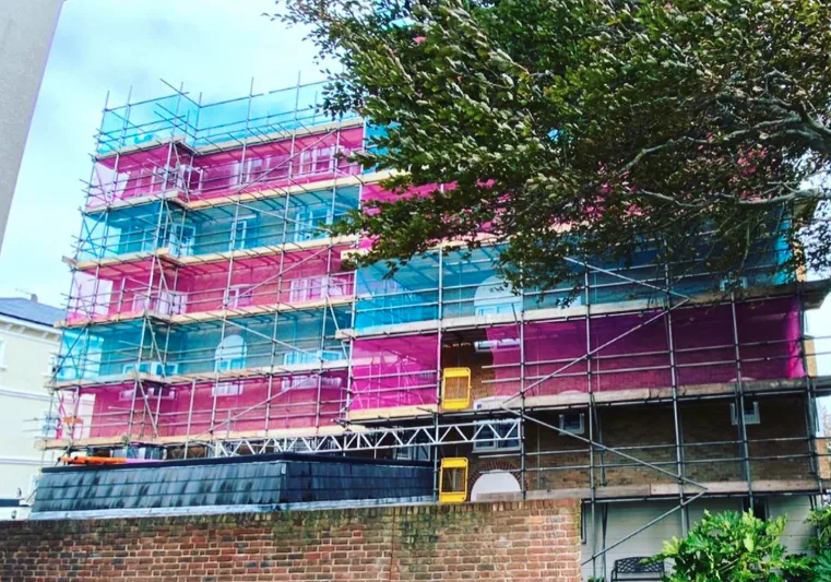 Multi-storey commercial scaffolding with coloured debris netting on a town centre building in West Sussex by A-Star Scaffolding Southern Ltd