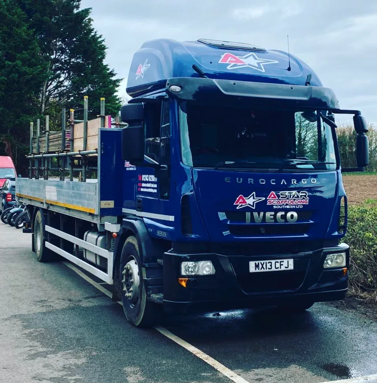 A-Star Scaffolding Southern Ltd branded Iveco Eurocargo flatbed truck loaded with scaffolding poles, West Sussex