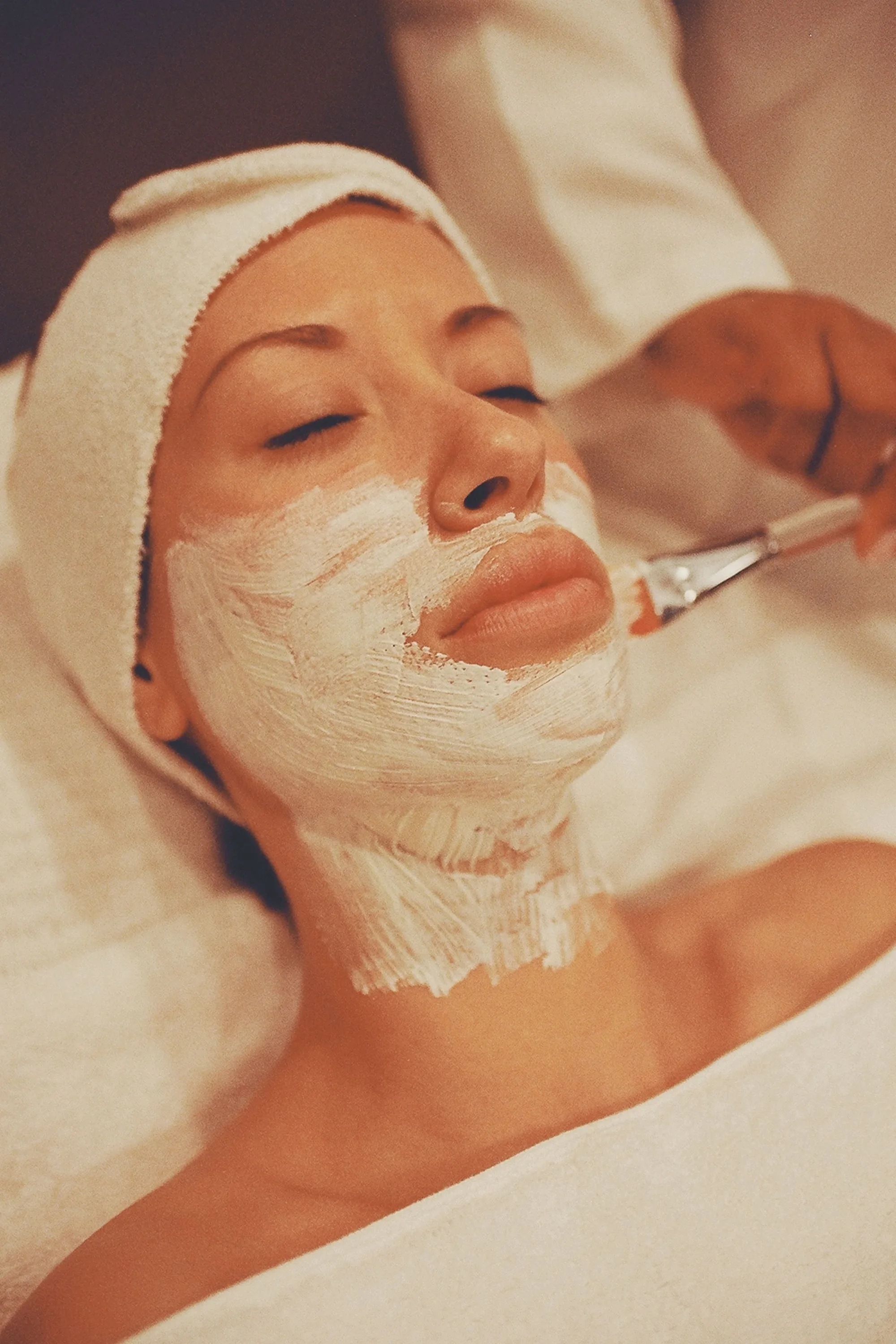 Client relaxing with a facial mask being applied during a skincare treatment at Novauria Aesthetics.