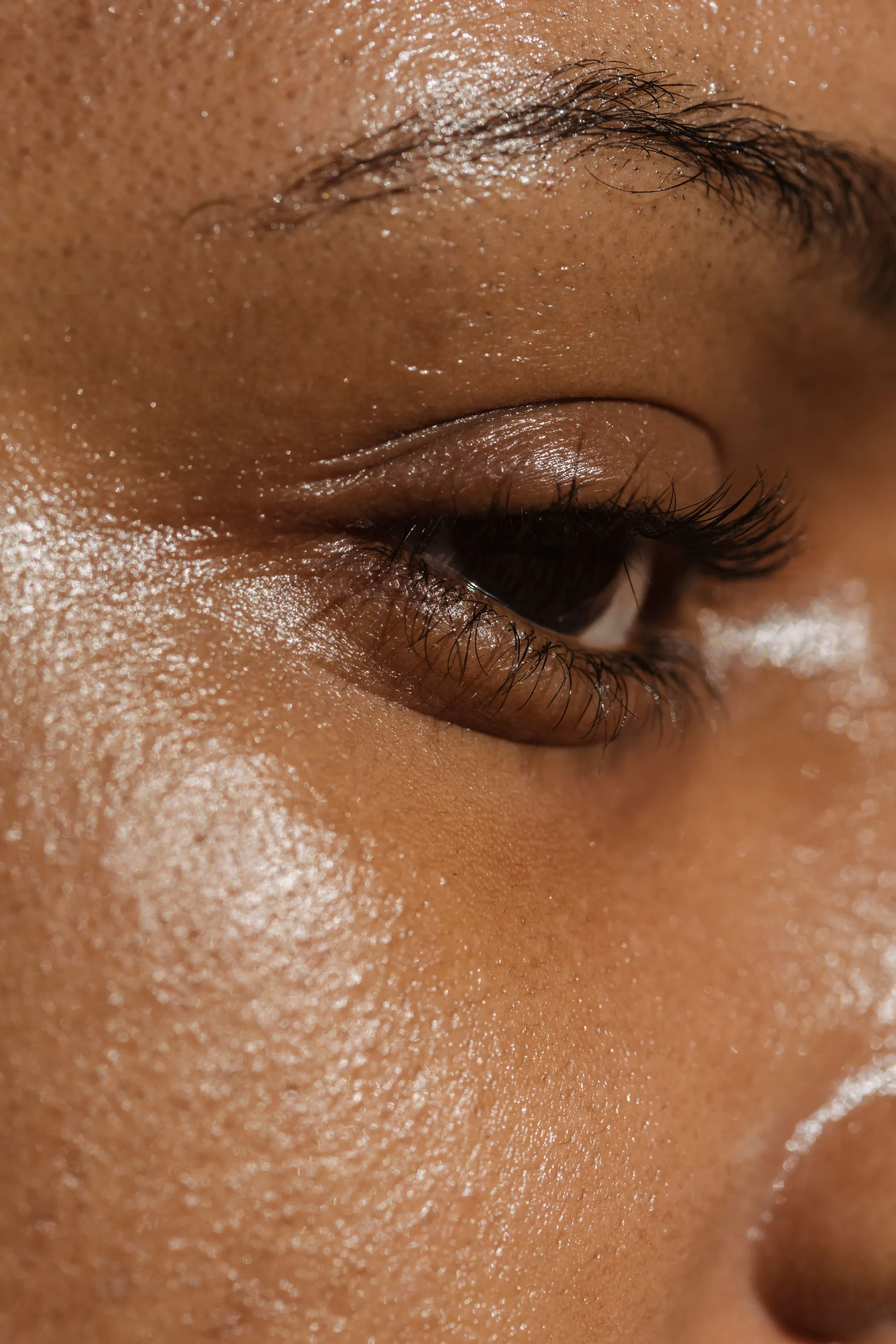 Extreme close-up of hydrated, glowing under-eye skin — the plump, dewy finish clients look for from skin booster treatments.